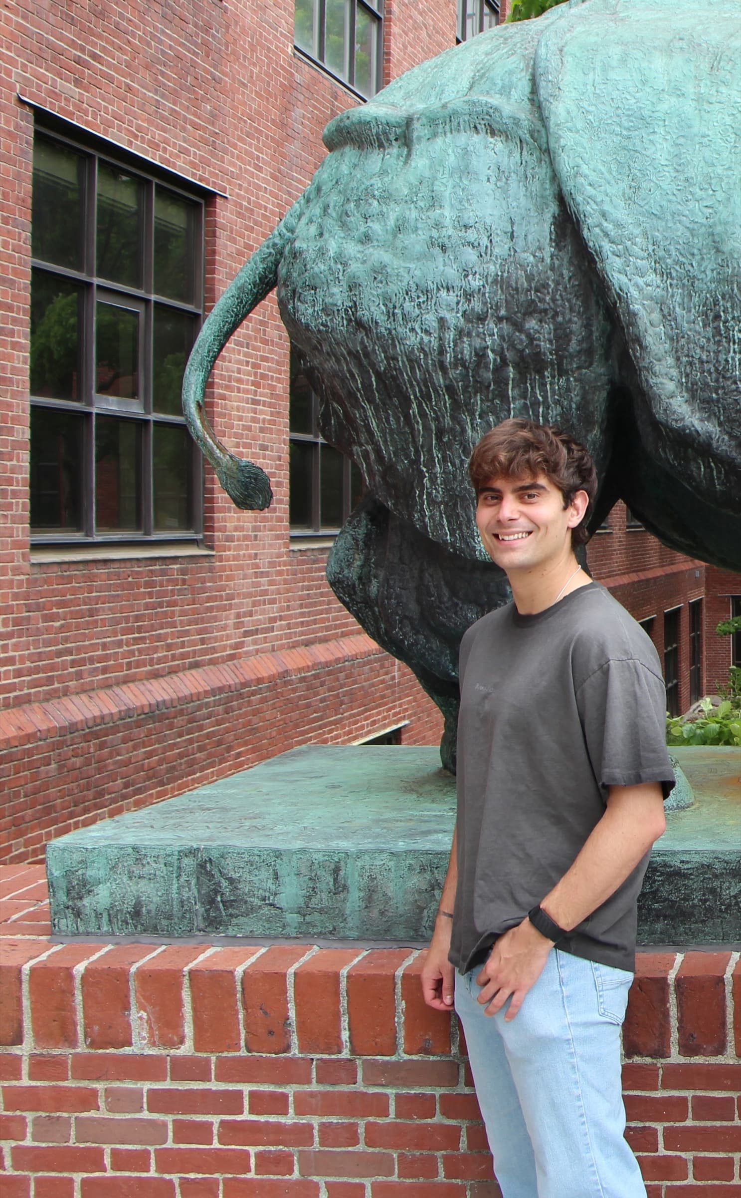Marc Duque Ramírez standing beside a sculpture at Harvard