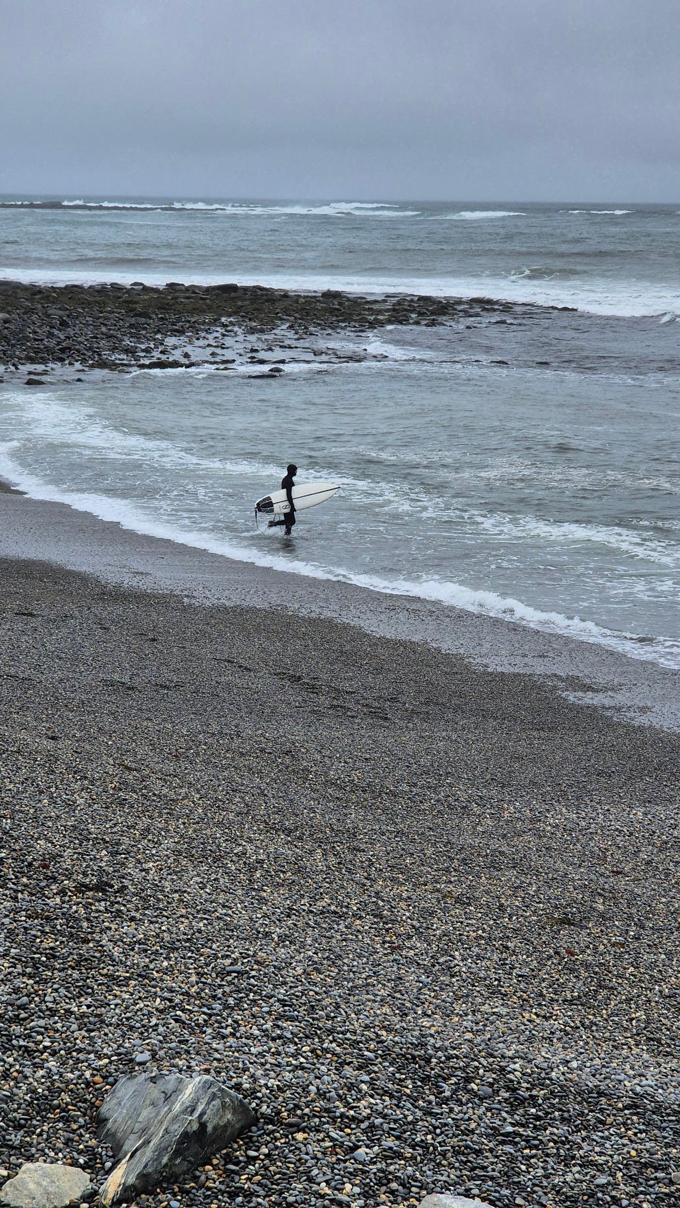 Marc walking into the ocean with a surfboard
